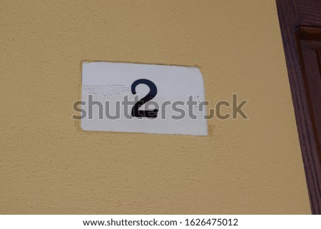 Number tag on the wall of an house with "2" written on it