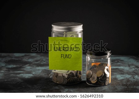 EMERGENCY FUND wordings on a paper stucked on a jar full of coins