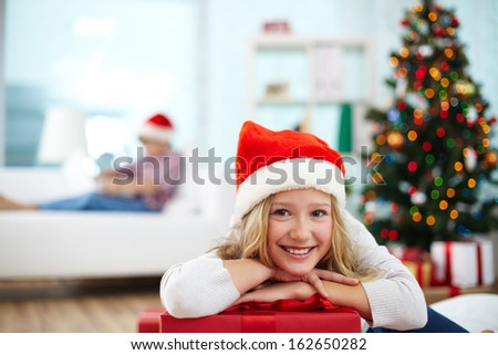 Portrait of happy girl with big red giftbox looking at camera on Christmas evening
