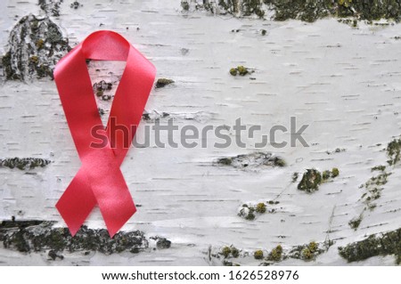 A red ribbon attached to a birch is an international symbol of the fight against AIDS. There is space for inscription.