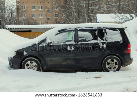Car on a city street in winter covered with snow.