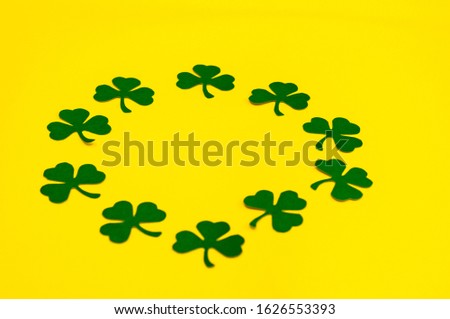 Happy Saint Patrick's of handmade paper clover leaves on yellow background with copy space.