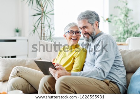 portrait of happy smiling senior couple using tablet at home Royalty-Free Stock Photo #1626555931