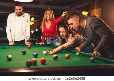 Group of friends play billiards at night out Royalty-Free Stock Photo #1626562438