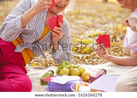 Close up picture of a picnic blanket with two ladies playing cards