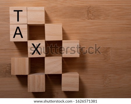 Tax with wooden alphabet blocks, on plank wooden background with copy space