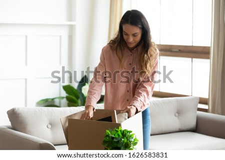Millennial Caucasian wife unpack cardboard boxed moving to new house or apartment, excited young woman open carton parcel package in living room settle at own home, relocation, ownership concept Royalty-Free Stock Photo #1626583831