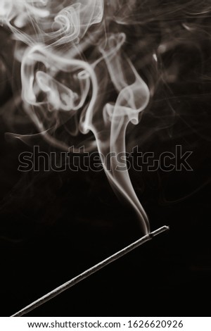sepia toned black and white vertical photo of a smoking incense stick