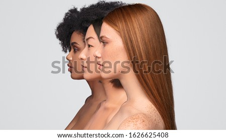 Side view of pretty diverse ladies with clean skin standing in row while representing skincare industry against gray background Royalty-Free Stock Photo #1626625408