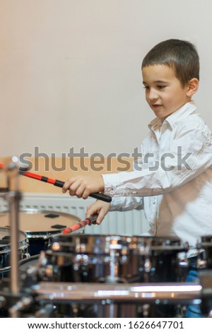 Boy drumming. boy in a white shirt plays the drums. vertical photo.