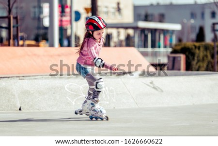 little cute girl riding on roller skates on the bike path