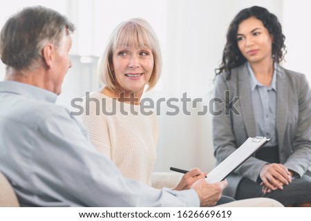 Senior Health Insurance Concept. Mature couple making agreement with sale agent, senior woman signing contract