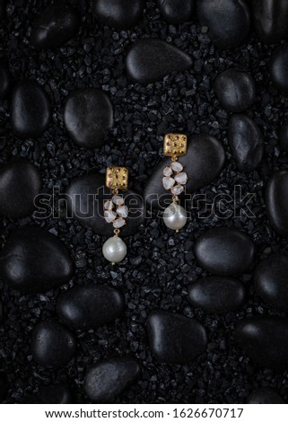 Close-up of two pearl earring on Black stones background