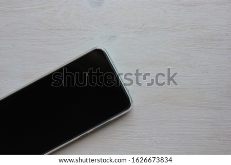 The smartphone lies on a light wooden background.