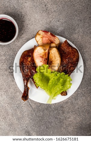 Roasted duck leg with apples on a plate. Top view.