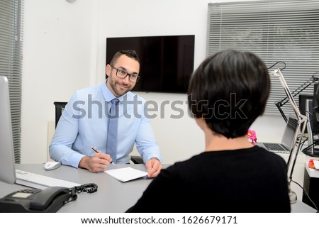 handsome business man with a female client signing contract agreement and shaking hands in office