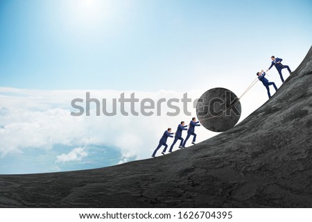 Teamwork example with business people pushing stone to top Royalty-Free Stock Photo #1626704395