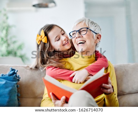 Grandmother and granddaughter having fun together and reading a book at home Royalty-Free Stock Photo #1626714070