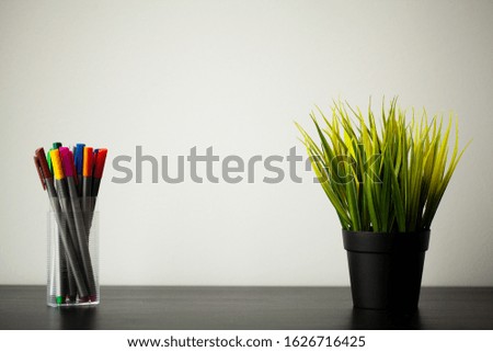 Set of markers in a plastic cup on wood table.