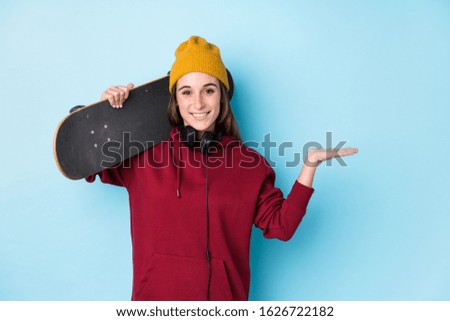 young skater caucasian woman isolated showing a copy space on a palm and holding another hand on waist.