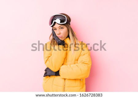 Young caucasian woman wearing a ski clothes in a pink background who is bored, fatigued and need a relax day.