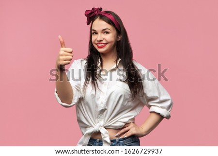 Body language. Portrait of cheerful beautiful curvy brunette young Caucasian female wearing extravagant clothes and bright make up approving good idea, making thumbs up gesture, smiling broadly