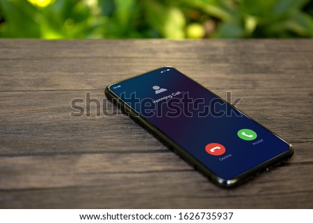 Phone with incoming call on the screen table background of nature Royalty-Free Stock Photo #1626735937
