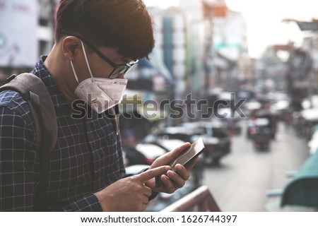 Concept of coronavirus quarantine. MERS-Cov, Novel coronavirus (2019-nCoV), man with medical face mask using the phone to search for news.Air pollution  Royalty-Free Stock Photo #1626744397