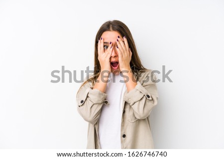 Young caucasian woman  isolated blink through fingers frightened and nervous.