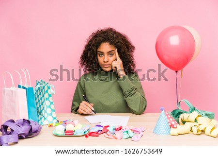 Young african american woman planning a birthday pointing temple with finger, thinking, focused on a task.