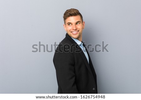 Young handsome caucasian man looks aside smiling, cheerful and pleasant.