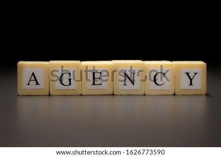 The word AGENCY written on wooden cubes isolated on a black background...