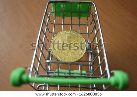 Bitcoin inside mini shopping trolley as in business creative concept. Cryptocurrency background.