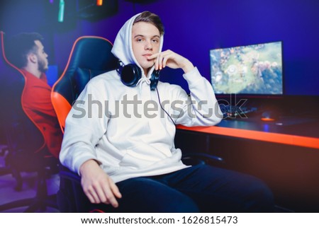 Professional gamer playing tournaments online video games computer with headphones, red and blue.