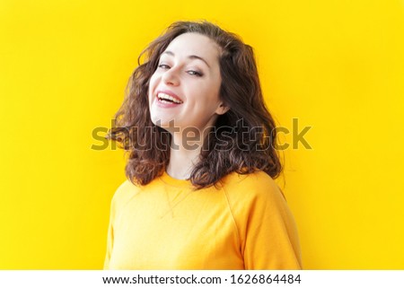 Happy girl smiling. Beauty portrait young happy positive laughing brunette woman on yellow background isolated. European woman. Positive human emotion facial expression body language.