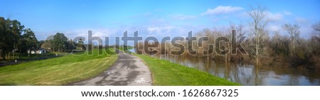Paved bike path on top of earthen dike levee along Mississippi River in Louisiana  Royalty-Free Stock Photo #1626867325
