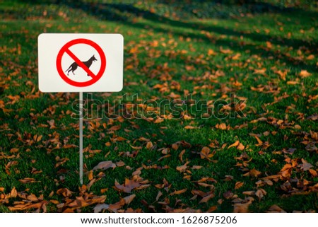The sign is forbidden to walk dogs installed on the lawn in the park