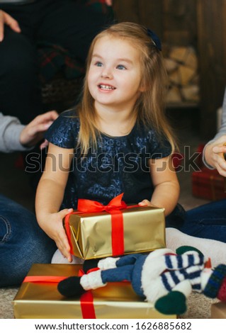 Beautiful little girl near the Christmas tree. Happy family celebrates new year. A child opens a new year's gift.
