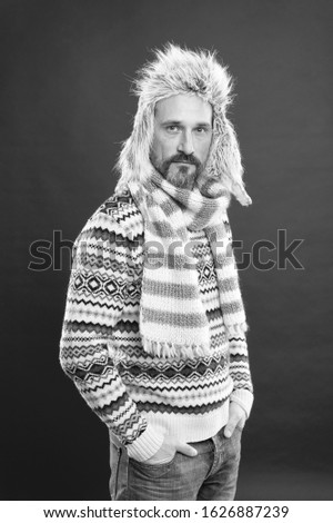 Warming up. Faux fur. Menswear concept. Fashion collection. Fashion clothes. Knitted accessories. Cold winter conditions. Handsome bearded man wearing hat and scarf red background. Winter fashion.