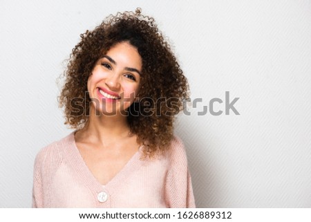Close up portrait of smiling young african american woman with curly hair by white background