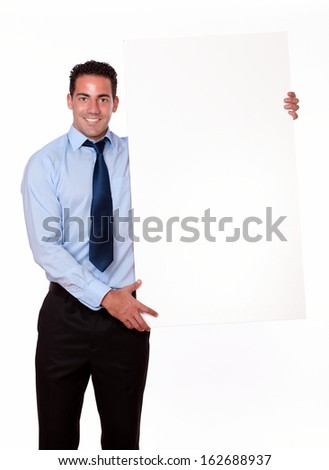 Portrait of an attractive man on blue shirt and tie holding a blank placard while standing and smiling at you on isolated background - copyspace