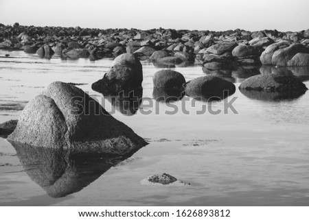 Manche, Normandy, France. Beautiful sea coast with boulders reflected in calm water. Majestic nature art background. Eco-planet concept. Moody solitude landscape. Black white historic photo.