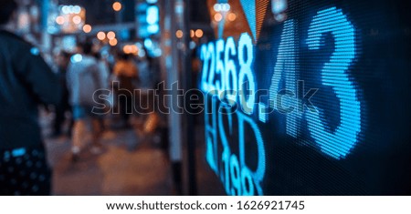Financial stock exchange market display screen board on the street with and city light reflections, selective focus