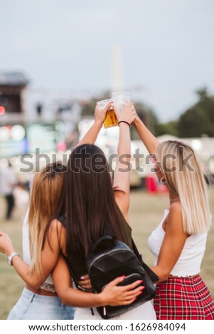 Back view of female friends toasting with beer