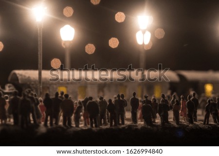 Silhouettes of a crowd standing at old vintage train on foggy background. Selective focus. Creative artwork decoration with toy train