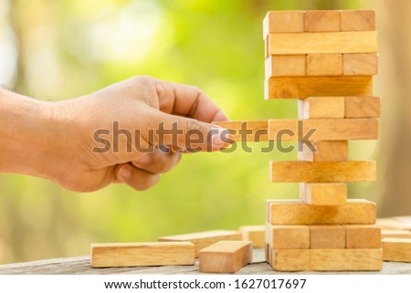 Close up hand holding blocks wood game on blurred green background. With copy space for text or design concept