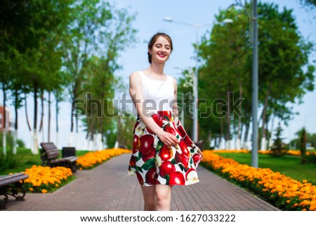 Close up, Young beautiful brunette girl in summer dress walks in the park