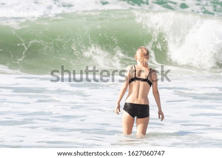 A fragile girl standing in front of an approaching wave