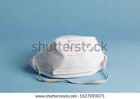 a 95 percent standard particulate face mask sometimes used for protection from airborne viruses such as SARS and Corona virus on a blue background Royalty-Free Stock Photo #1627093075