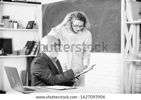 Student asking teacher about task. Solving math tasks. School education concept. Check homework. Educator and student looking at book. Explaining difficult topic. Student puzzled by some information.
